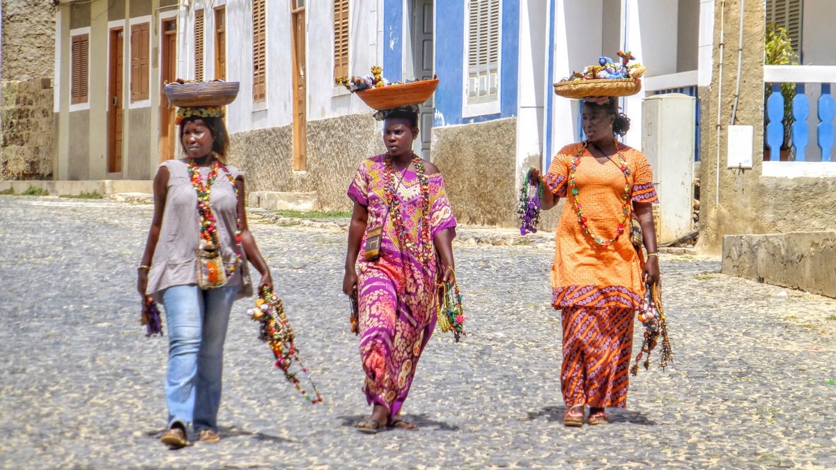 Drei Frauen auf Kapverden balancieren ihre Körbe auf dem Kopf. Foto: Belinda Fewings / Unsplash