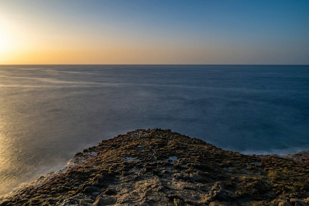 the sun is setting over the ocean on the horizon