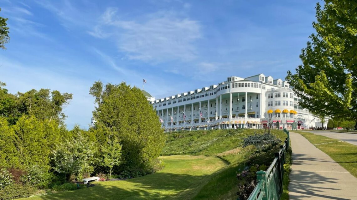 a large white building sitting on top of a lush green hillside